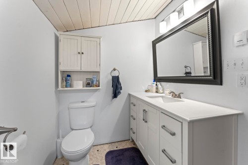 White vanity with an integrated sink and brushed nickel faucet, large framed mirror, and wood-paneled ceiling - #421 61209 Rge Rd 465, Rural Bonnyville M.D., AB 