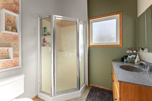 Corner shower enclosure with textured glass, wood-framed window, and vanity with an integrated sink - #421 61209 Rge Rd 465, Rural Bonnyville M.D., AB 