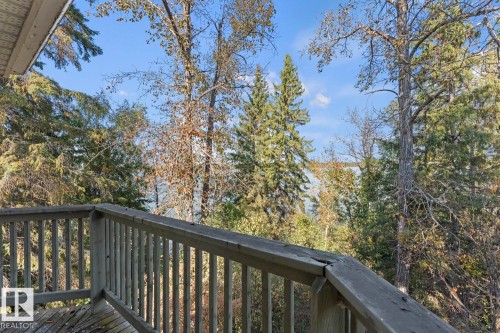 Wood deck with timber railings overlooking a wooded landscape and distant water - #421 61209 Rge Rd 465, Rural Bonnyville M.D., AB 