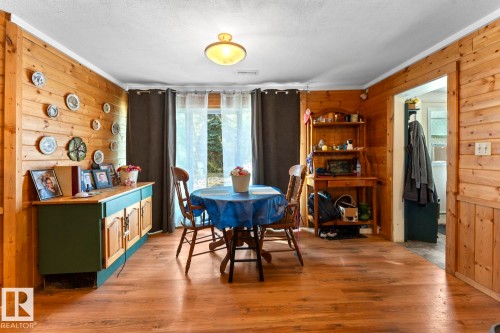 Wood-finish flooring, wood plank wall paneling, ceiling-mounted light fixture, and a window with sheer and blackout curtains - #421 61209 Rge Rd 465, Rural Bonnyville M.D., AB 