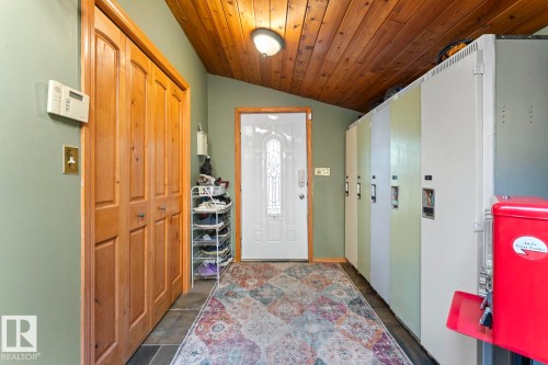 Wood-paneled ceiling, entry door with decorative glass, wood-finish bi-fold doors, and slate tile flooring - #421 61209 Rge Rd 465, Rural Bonnyville M.D., AB 