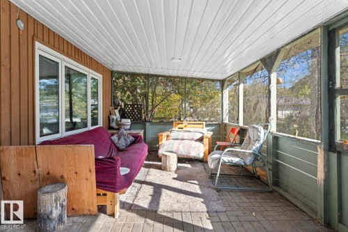 Enclosed porch featuring a wood-paneled wall and screened openings - #421 61209 Rge Rd 465, Rural Bonnyville M.D., AB 