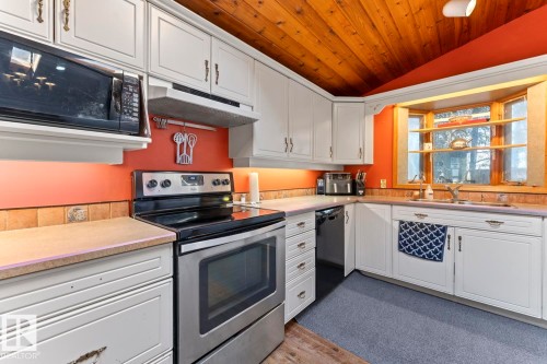 White cabinetry, stainless steel appliances, wood-finish ceiling, and a large bay window - #421 61209 Rge Rd 465, Rural Bonnyville M.D., AB 
