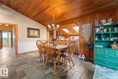 Angled wood-paneled ceiling, wood-paneled wall accent, beadboard wainscoting, and large format stone tile flooring - #421 61209 Rge Rd 465, Rural Bonnyville M.D., AB 