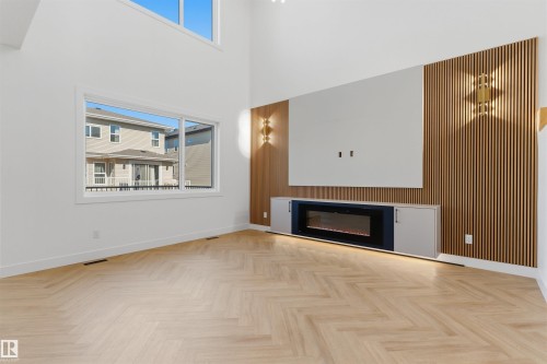 Vaulted ceiling, herringbone wood-finish flooring, built-in entertainment center with electric fireplace, built-in cabinetry, and wall-mounted sconces - 2720 63 Avenue, Rural Leduc County, AB 