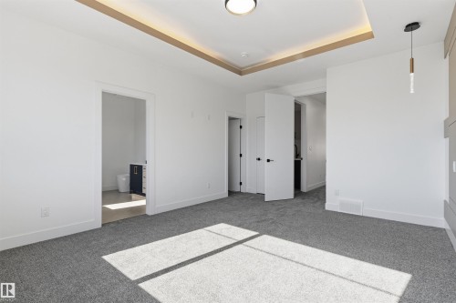 Recessed ceiling with perimeter lighting, ceiling-mounted light fixture, pendant light fixture, and gray textured carpeting - 2720 63 Avenue, Rural Leduc County, AB 