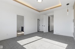 Recessed ceiling with perimeter lighting, ceiling-mounted light fixture, pendant light fixture, and gray textured carpeting - 