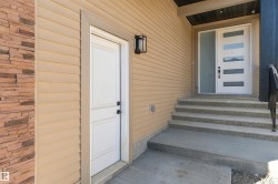 Modern entry with a multi-paneled front door and frosted sidelight, featuring a concrete staircase with textured risers, and a stone veneer accent wall - 