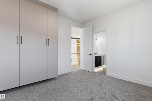 Built-in wardrobe storage, gray carpeting, white walls, and a white interior door with dark hardware - 2720 63 Avenue, Rural Leduc County, AB 