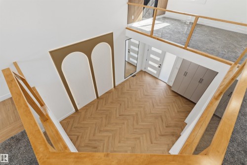 Open concept entrance with herringbone wood-finish flooring, a decorative wall panel with integrated lighting, and a grey built-in storage unit - 2720 63 Avenue, Rural Leduc County, AB 