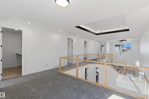 Carpeted loft featuring a tray ceiling with recessed lighting, a modern chandelier, and a built-in desk area - 2720 63 Avenue, Rural Leduc County, AB 