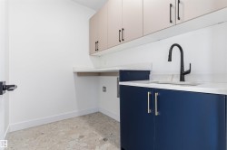 Built-in cabinetry with contrasting finishes, undermount sink, matte black gooseneck faucet, light-toned countertop, and terrazzo-style flooring - 