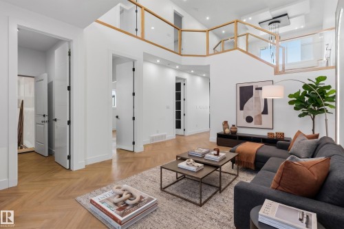 Two-story living area with high ceilings, recessed lighting, wood-finish flooring, and a second-level balcony with glass railing - 2720 63 Avenue, Rural Leduc County, AB 