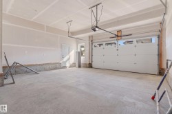 Spacious garage with exposed concrete flooring, white overhead garage door, built-in window, and interior access door - 