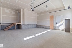 Concrete flooring, drywall walls, overhead lighting, garage door track system, and interior access door - 