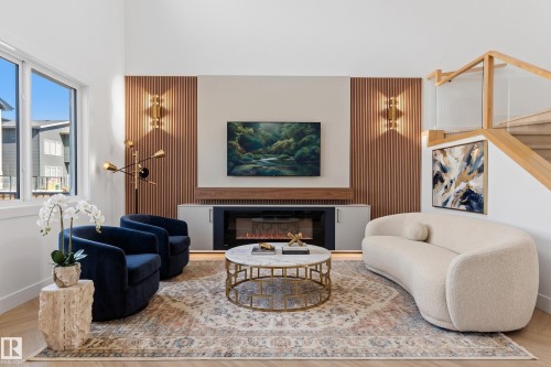 Hardwood flooring with a modern fireplace, integrated built-in cabinetry, and a wood-slat accent wall - 2720 63 Avenue, Rural Leduc County, AB 