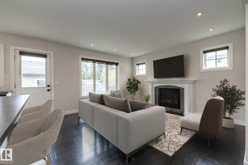 Living space featuring dark wood-finish flooring, recessed lighting, and a white mantel fireplace with a dark tile surround - 55 Michigan Street, Devon, AB 