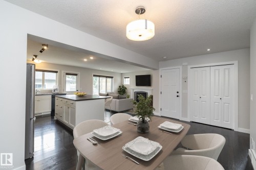 Open-concept layout featuring dark wood-finish flooring, a kitchen island with a dark countertop, white shaker cabinetry, and a bi-fold closet - 55 Michigan Street, Devon, AB 