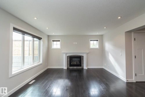 Dark wood-finish flooring, white trim, recessed lighting, and a fireplace with a white mantel and tile surround - 55 Michigan Street, Devon, AB 