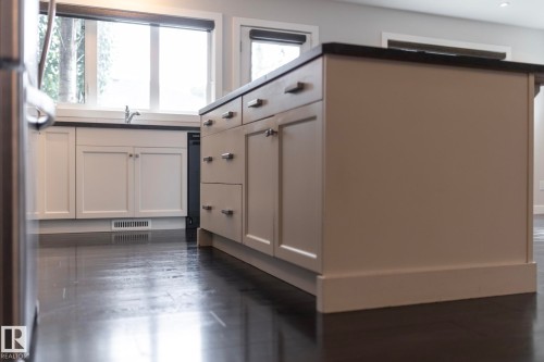 Kitchen island with countertop, under-sink cabinetry, built-in dishwasher, and wood-finish flooring - 55 Michigan Street, Devon, AB 
