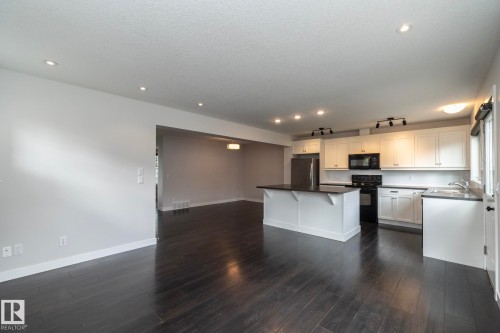 Kitchen with dark wood-finish flooring, white cabinetry, dark countertops, and stainless steel appliances - 55 Michigan Street, Devon, AB 
