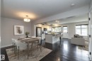 Open-concept layout featuring dark wood-finish flooring, a kitchen island with seating, stainless steel appliances, and white cabinetry - 55 Michigan Street, Devon, AB 