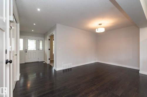 Dark wood-finish flooring throughout, white interior doors with dark hardware, recessed ceiling lighting, and a modern ceiling light fixture - 55 Michigan Street, Devon, AB 