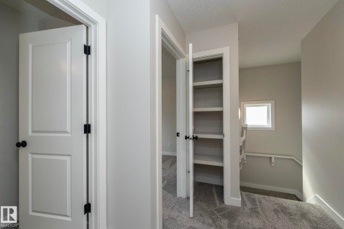 Hallway with carpet flooring, white paneled doors, built-in shelving, and a window providing natural light - 55 Michigan Street, Devon, AB 