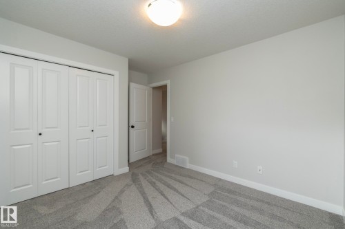 Light gray painted walls, recessed lighting, gray patterned carpet flooring, white bi-fold closet doors, and white interior doors - 55 Michigan Street, Devon, AB 