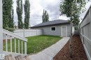 Landscaped backyard with a manicured lawn, concrete pathway, and a privacy fence - 55 Michigan Street, Devon, AB 