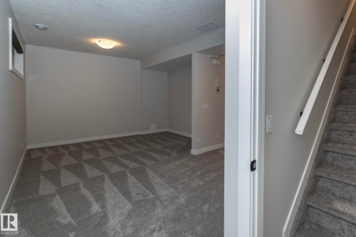 Spacious room with patterned carpeting, neutral wall finishes, and a single light fixture - 55 Michigan Street, Devon, AB 
