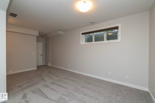 Recessed window with white trim, flush-mount ceiling light, light-toned walls, and patterned carpeting - 55 Michigan Street, Devon, AB 
