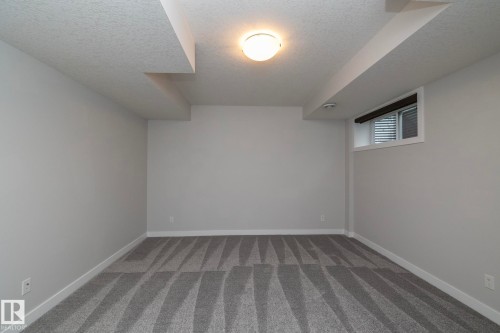 Room featuring patterned gray carpeting, white walls, a single ceiling-mounted light fixture, and a window with blinds - 55 Michigan Street, Devon, AB 