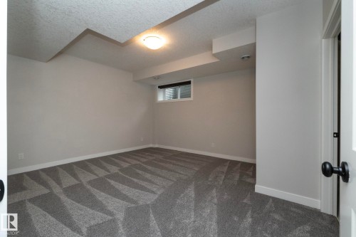 Recessed window with horizontal blinds, overhead ceiling light fixture, geometric patterned carpet, and light gray wall finish - 55 Michigan Street, Devon, AB 