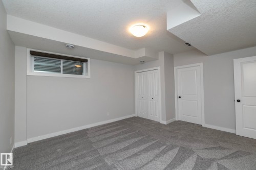 Recessed window with blinds, light gray walls, textured gray carpet, white trim, and white doors with dark hardware - 55 Michigan Street, Devon, AB 
