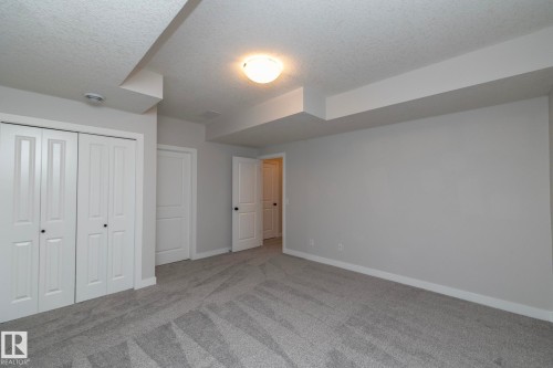 Neutral grey wall paint, plush grey patterned carpeting, white trim, white panel doors, and a ceiling-mounted light fixture - 55 Michigan Street, Devon, AB 