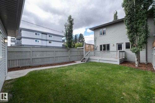 Spacious backyard featuring a large deck with railings, a manicured lawn, and a privacy fence - 55 Michigan Street, Devon, AB 
