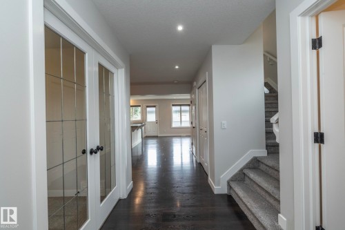 Dark wood-finish flooring, recessed lighting, white trim throughout, and a carpeted staircase - 55 Michigan Street, Devon, AB 