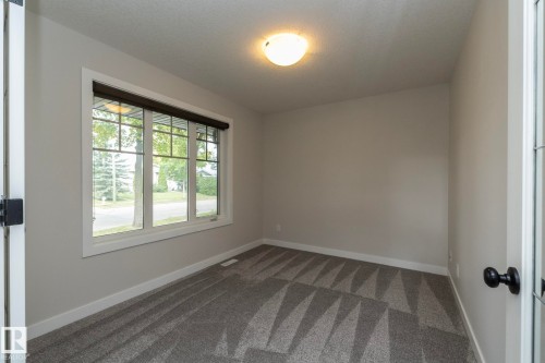Neutral wall color, patterned carpet flooring, triple-pane window, flush mount ceiling light fixture, and white trim - 55 Michigan Street, Devon, AB 