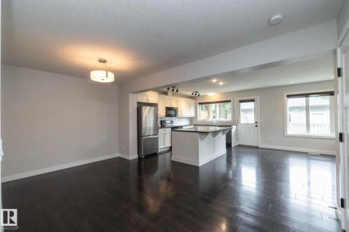 Open-concept living space with dark wood-finish flooring, white walls, and a modern ceiling fixture - 55 Michigan Street, Devon, AB 