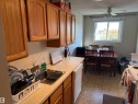 Wood-finish cabinetry, solid surface countertops, stainless steel sink, and durable tile flooring - #414 3611 145 Av Nw, Edmonton, AB 