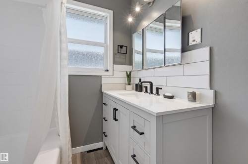 White shaker vanity with black hardware, white countertop, white subway tile backsplash, and a medicine cabinet with integrated lighting - 13655 122 Avenue Nw, Edmonton, AB 