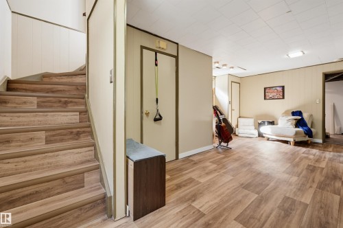 Wood-finish flooring throughout, paneled walls, and a drop ceiling with recessed lighting - 13655 122 Avenue Nw, Edmonton, AB 