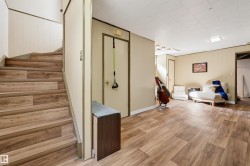 Wood-finish flooring throughout, paneled walls, and a drop ceiling with recessed lighting - 