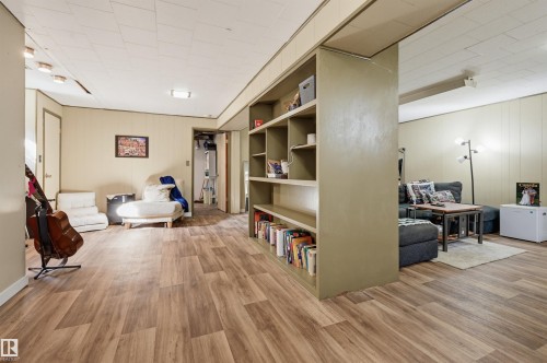 Spacious room featuring wood-finish flooring, built-in shelving, paneled walls, and recessed lighting - 13655 122 Avenue Nw, Edmonton, AB 