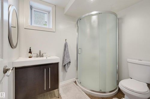 Contemporary vanity with integrated sink, curved glass shower enclosure, and modern toilet - 13655 122 Avenue Nw, Edmonton, AB 