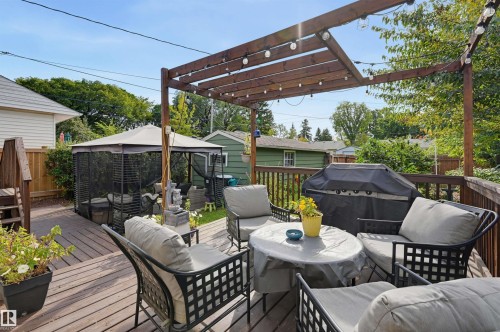 Spacious wood-finish deck with a pergola, string lighting, and a screened gazebo area - 13655 122 Avenue Nw, Edmonton, AB 