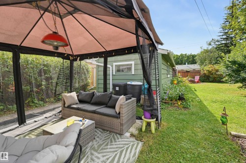 Attached patio canopy with screening, overhead heat lamp, and adjacent lawn area - 13655 122 Avenue Nw, Edmonton, AB 
