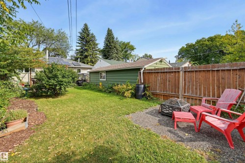 Expansive green lawn, wood fence perimeter, gravel patio area, and mature perimeter landscaping - 13655 122 Avenue Nw, Edmonton, AB 