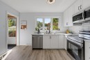 White cabinetry with matte black hardware, wood-finish flooring, stainless steel appliances, white subway tile backsplash, and a contemporary ceiling light fixture - 13655 122 Avenue Nw, Edmonton, AB 